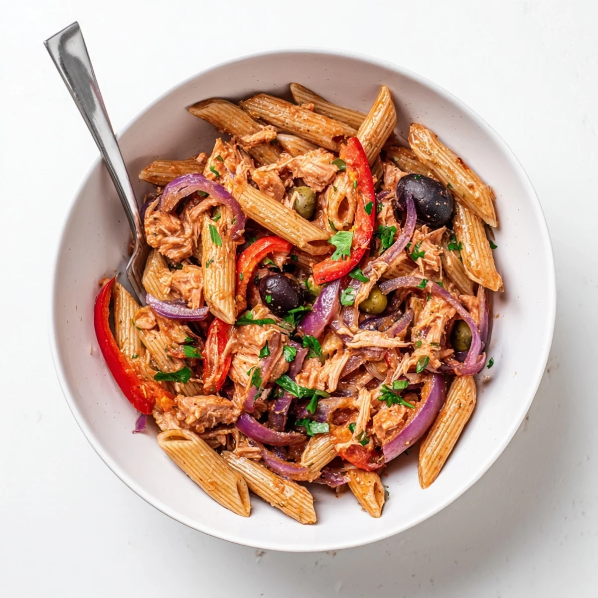 Deliciosa combinación de pasta, atún y pimientos rojos asados en un tazón vibrante.
