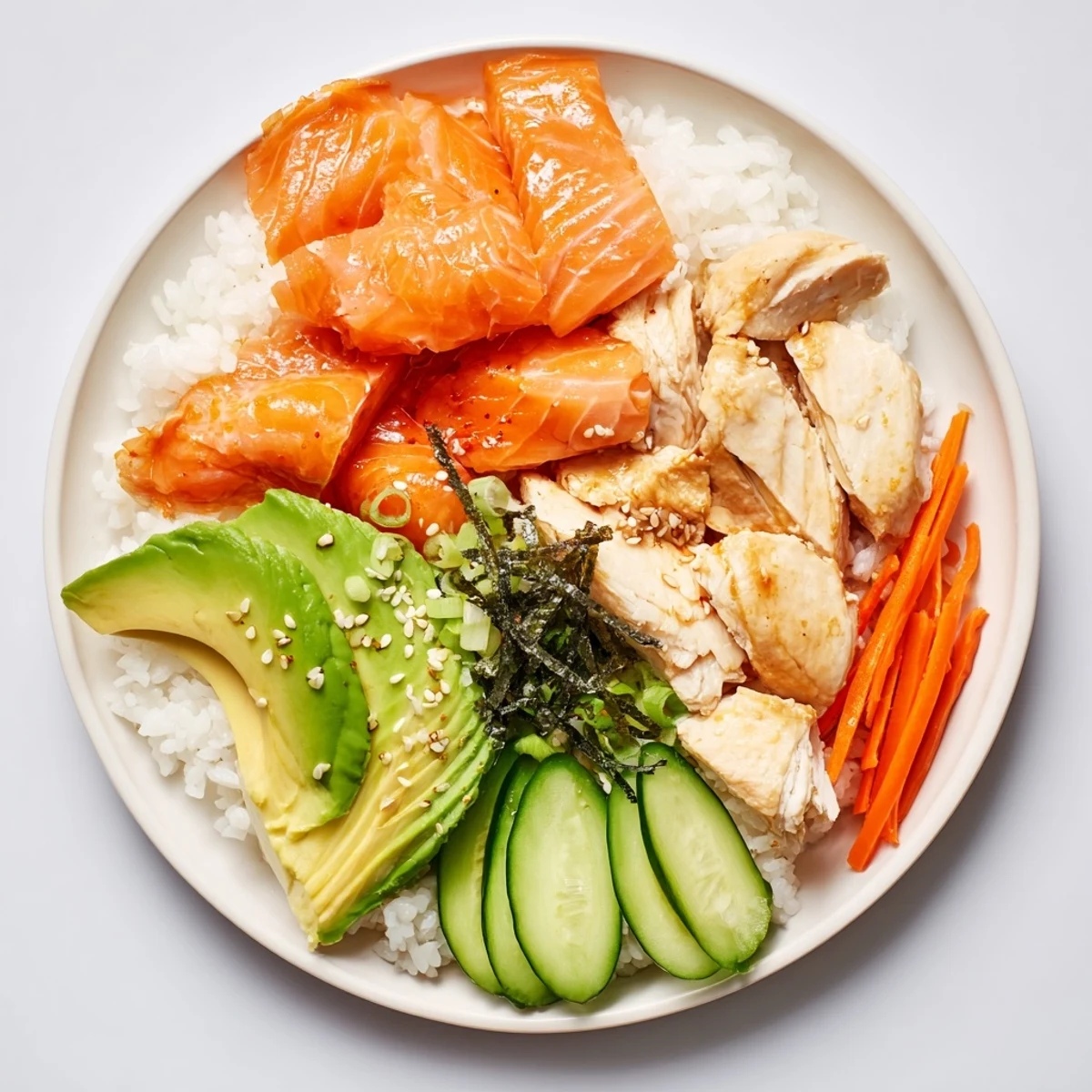 This Japanese-style Salmon & Chicken Rice Bowl features flaky salmon atop a bed of fluffy rice with avocado.