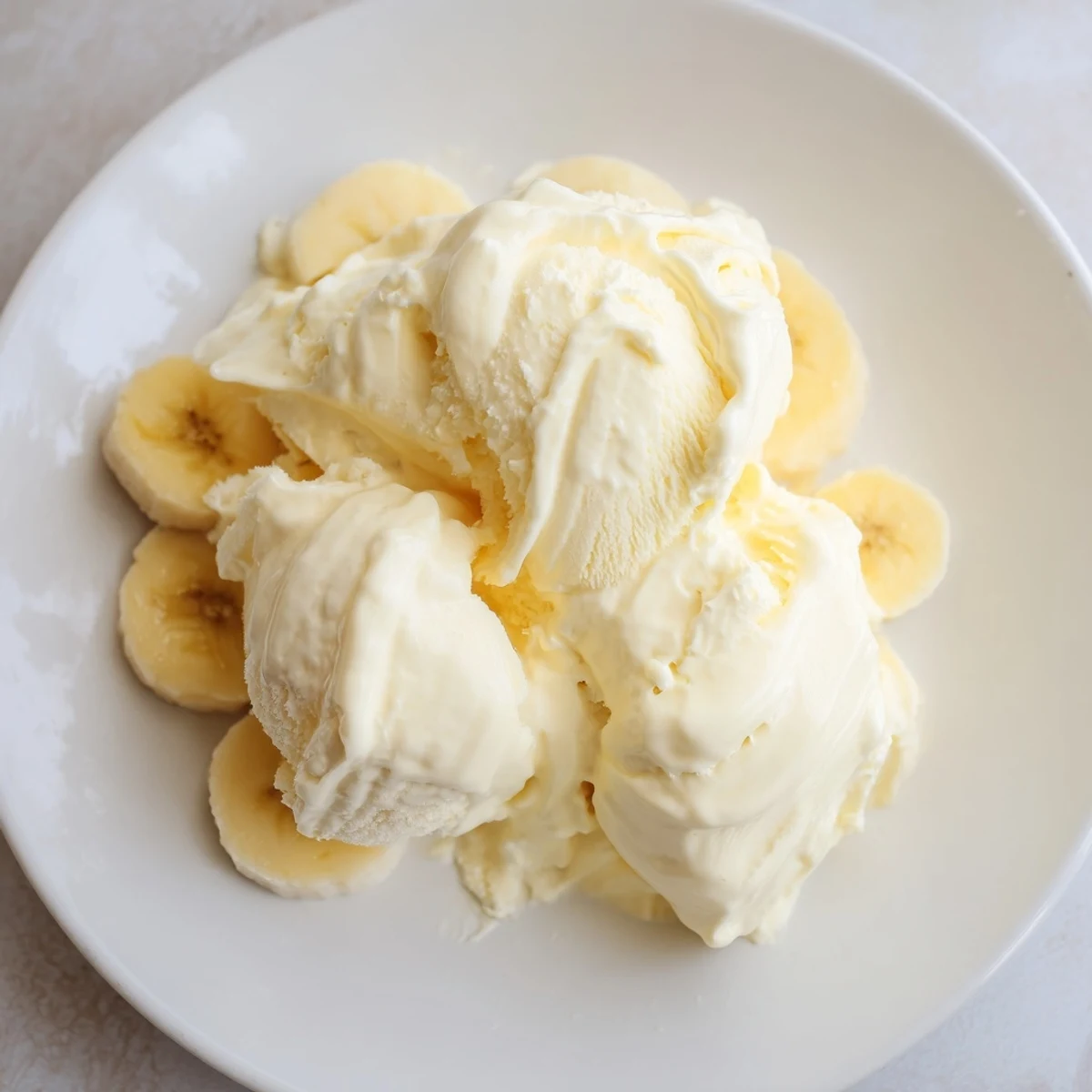 Frozen banana slices transforming into smooth 2-Ingredient Banana Ice Cream; a refreshing and healthy vegan delight.
