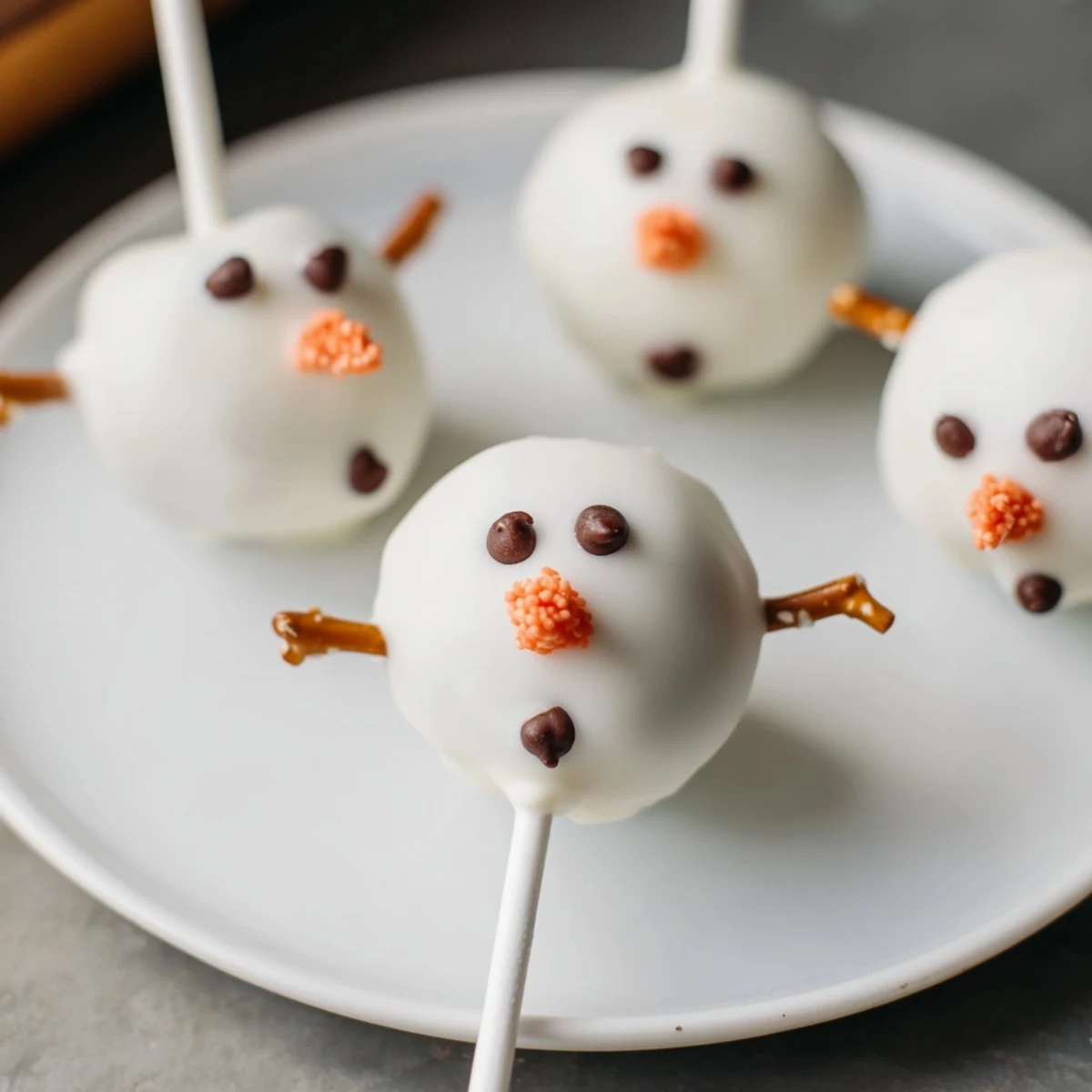 Close-up of freshly dipped Oreo Snowman Cake Pops, showcasing playful shapes and vibrant chocolate decorations.