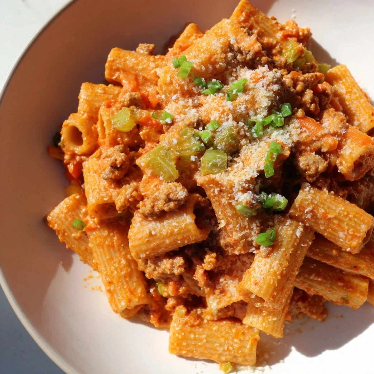A steaming bowl of kimchi ragu pasta, rich with a blend of Korean and Italian flavors.