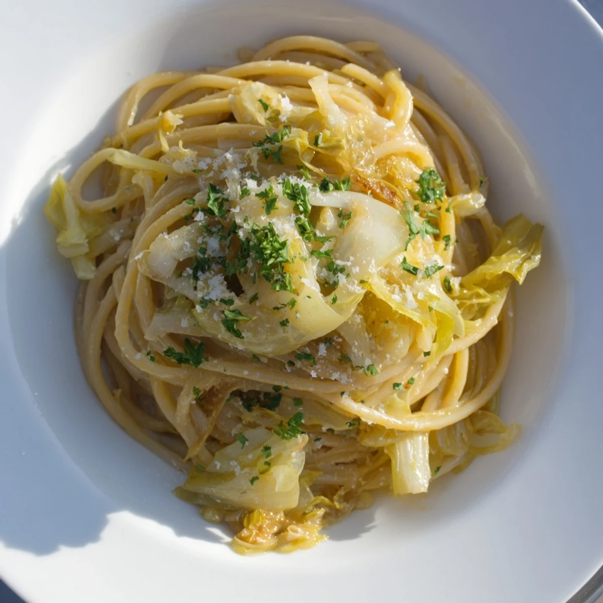 La pasta con repollo y ajo se sirve al dente, cubierta con Parmesano fundido y perejil fresco.
