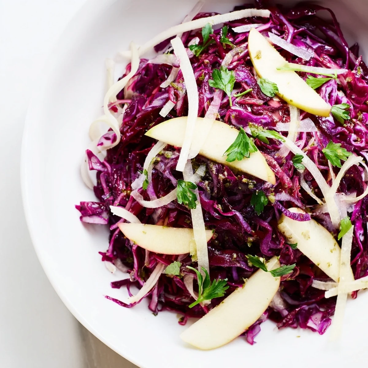 Una ensalada de col lombarda con manzana y parmesano en un bol, lista para servir como guarnición fresca.