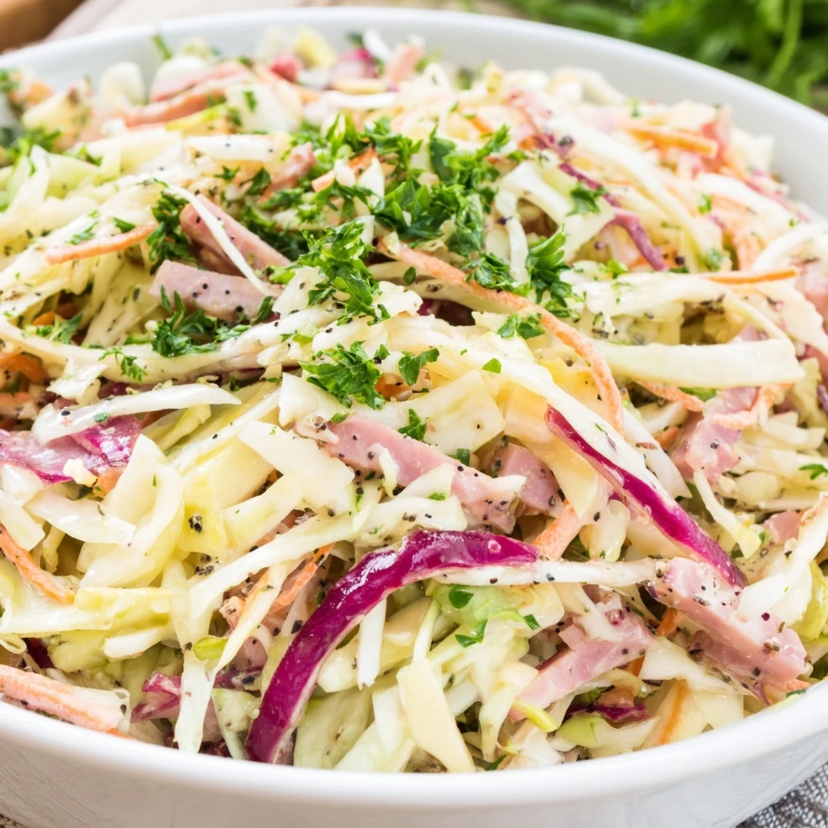 Plano cenital del German Cabbage Coleslaw With Shredded Ham, con aderezo cremoso y caraway seeds sobre las verduras.