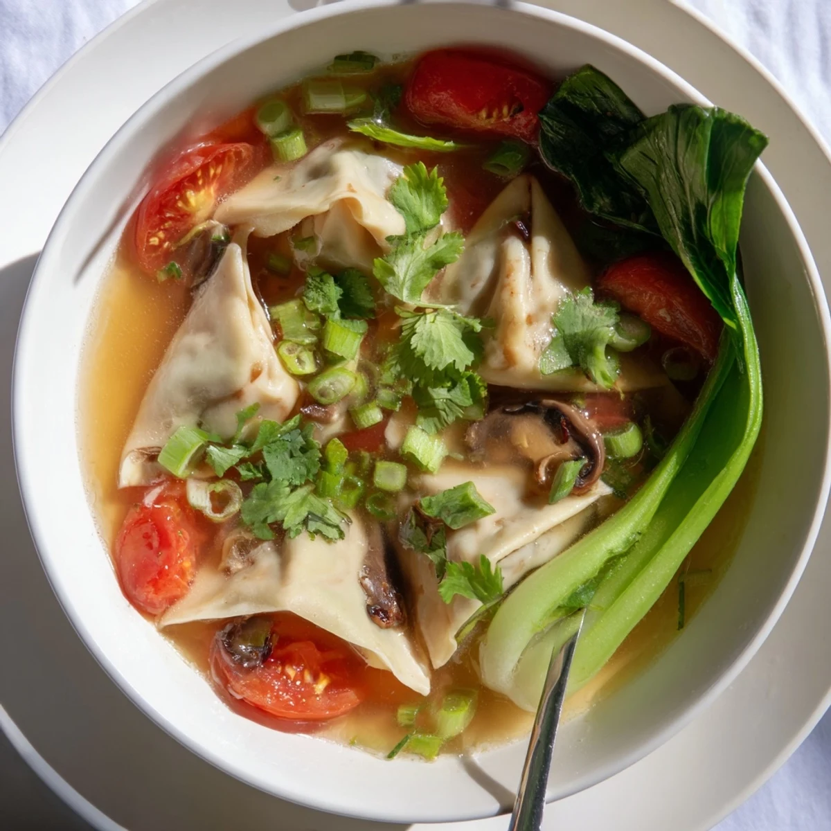 Steaming Tom Yum Wonton Soup in a ceramic bowl, showcasing tender wontons floating in aromatic Thai-inspired broth.
