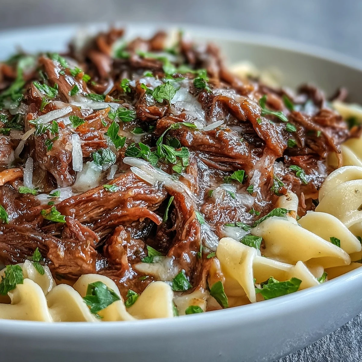 Crockpot French Onion Pot Roast Pasta servido con queso Gruyère derretido y perejil fresco sobre fideos mantequilla