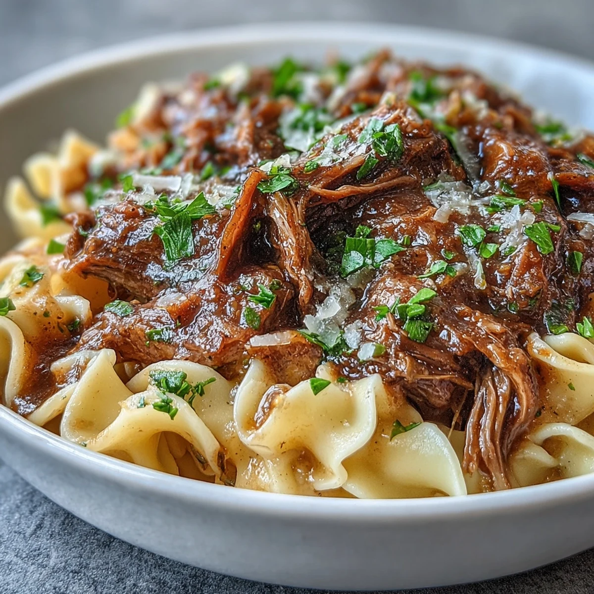Savory Crockpot French Onion Pot Roast Pasta twirled on a fork with rich onion gravy.