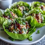 Spoonful of Potsticker Noodle Lettuce Cups into crisp butter lettuce leaves, offering a low-carb, Asian-inspired meal ready to enjoy.