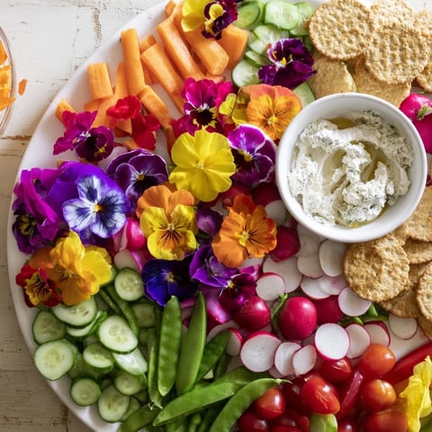 A vibrant Fairy Garden Platter with colorful edible flowers and fresh vegetables.