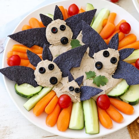 Creamy black bean dip transforms into spooky bat shapes on a Halloween platter.