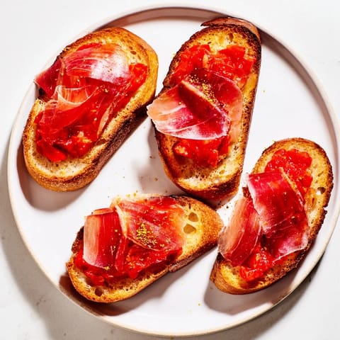 Freshly made pan con tomate, with juicy tomatoes and salty jamón, perfect appetizer.