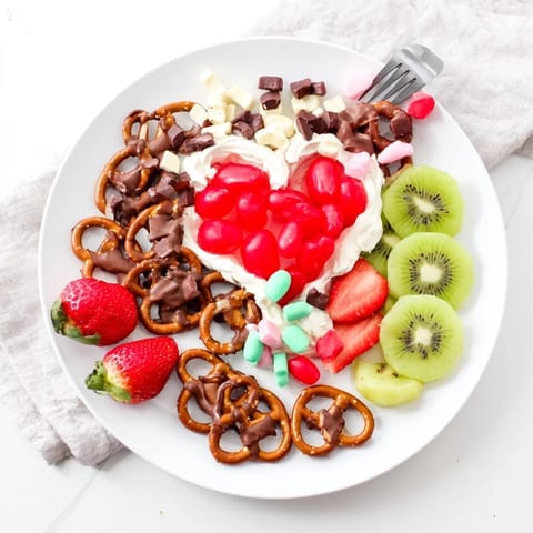 Vibrant Grinch's Heart Pretzel Board with pretzels, fruits and candies, perfect for holiday entertaining.