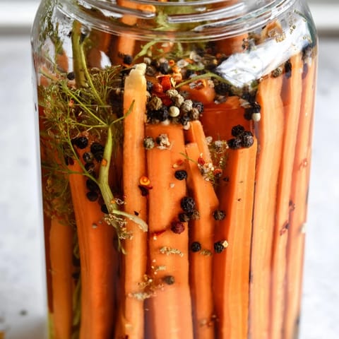 Close-up of Quick Pickled Carrot Spears, glistening with tangy brine and seasoned with spices.