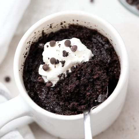 Freshly made Oreo Mug Cake, with whipped cream, ready for a quick, sweet treat.