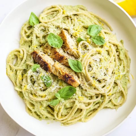 A close-up of creamy avocado chicken pasta with fresh basil, showcasing a rich and silky texture.
