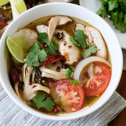 Aromática sopa Tom Yum Chicken servida hirviendo, con lemongrass y hojas de kaffir visibles, acompañada de arroz jazmín al lado.