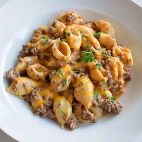 Una olla llena de conchas de pasta, carne de res y una salsa de tomate cremosa con un poco de perejil fresco por encima.