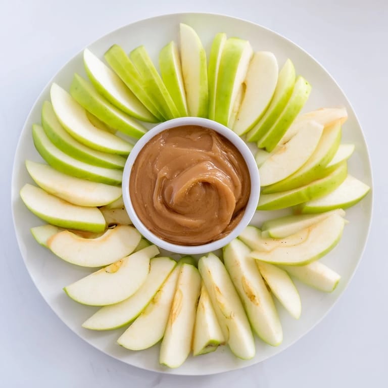 A close-up of a shareable platter of apple slices with rich, homemade caramel dip.