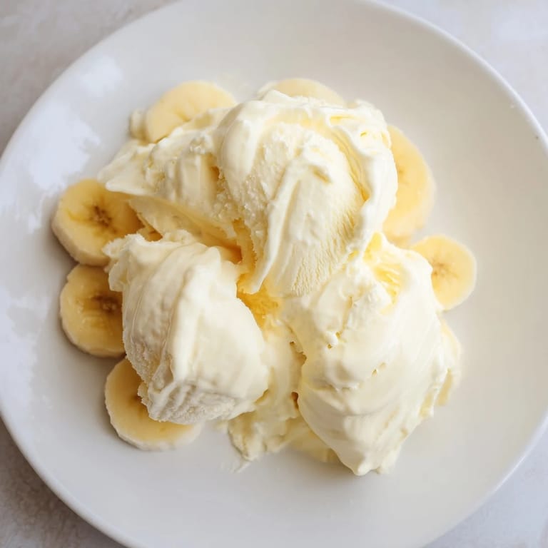 Frozen banana slices transforming into smooth 2-Ingredient Banana Ice Cream; a refreshing and healthy vegan delight.