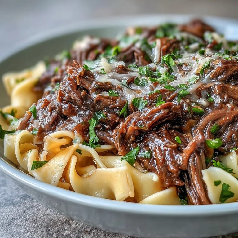 Crockpot French Onion Pot Roast Pasta en plato cremoso, carne tierna lenta con caramelo de cebollas y salsa rica
